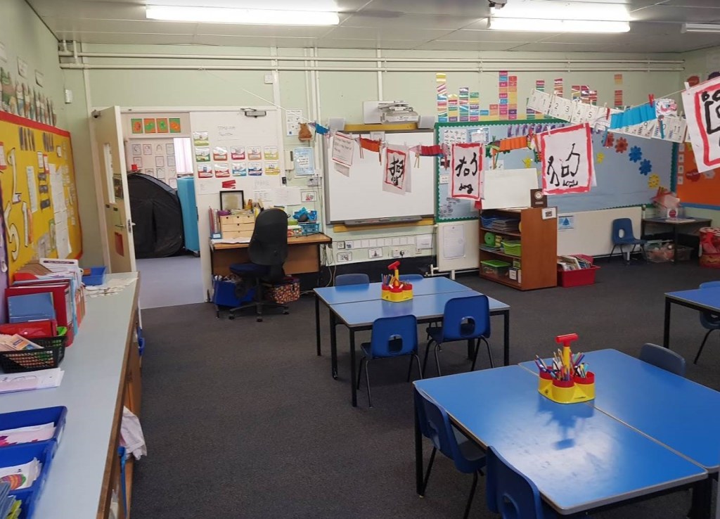 the classroom before, there are blue rectangular tables and blue plastic chairs