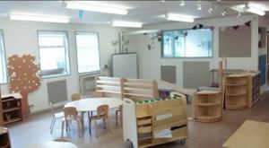 the teaching area is in the corner, textured pinboards and a wooden tree with fairy lights decorates the wall.