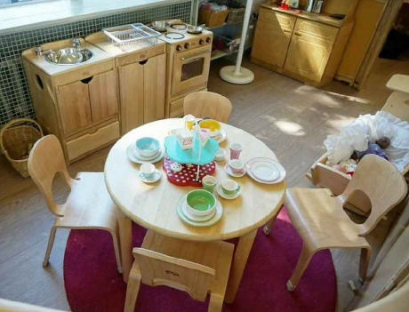 a home corner with wooden chairs and table, kitchen and kitchenware
