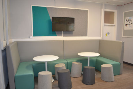 a TV is on the wall in the centre of the booth to view while seated