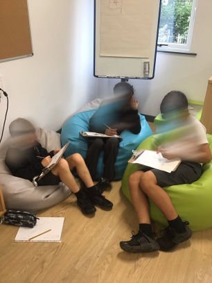three primary seven children sitting on beanbags to work