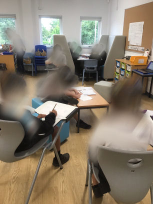 children working on the chairs with flip down desks