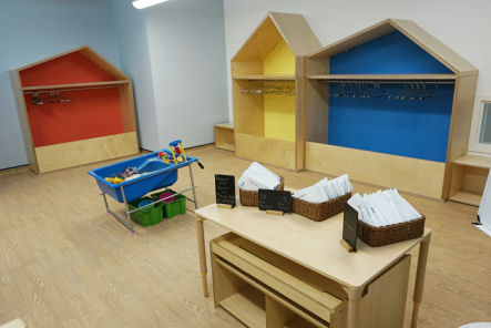 The cloakrooms are house shaped with the back painted in different colours, red, yellow and blue. there is a rail and coat hangers in each