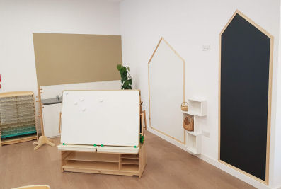 a creative area with two house shaped drawing boards on the wall, an art station and a drying rack
