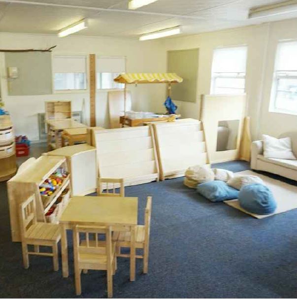 A reading corner with shelving cabinets that are low down for children to help themselves, beanbags and a sofa make it look like a living room