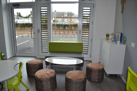 four stools that look like cut logs surround a coffee table, a sofa is by the window