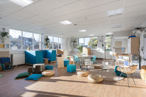 the room is bright and airy, there are plants hanging on the walls. the colour scheme is mostly natural wood with a few upholstered furnishings in blue.