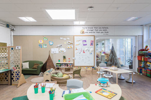 the ferry glen classroom has a half circle teaching table, a divider that has holes in it to see through, a cozy corner and a rectangular teaching table and inspirational quote on the wall