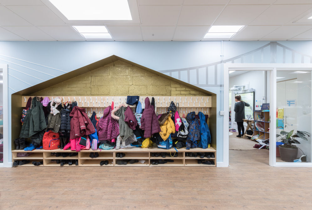 The cloakroom is shaped as a house, painted gold inside with coats and bags hanging on hooks and shoe storage beneath. on the walls is a graphic of two of the three Forth bridges. The door to the classroom has a big window to see in and out of the class