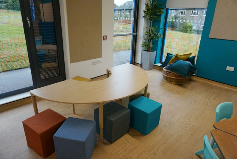 a U shaped teaching table with colourful upholstered cube stools around it