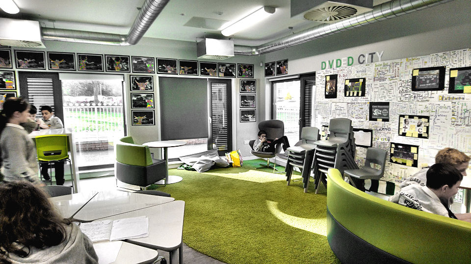 a comfy area of the classroom with a green carpet and round green grey sofas.