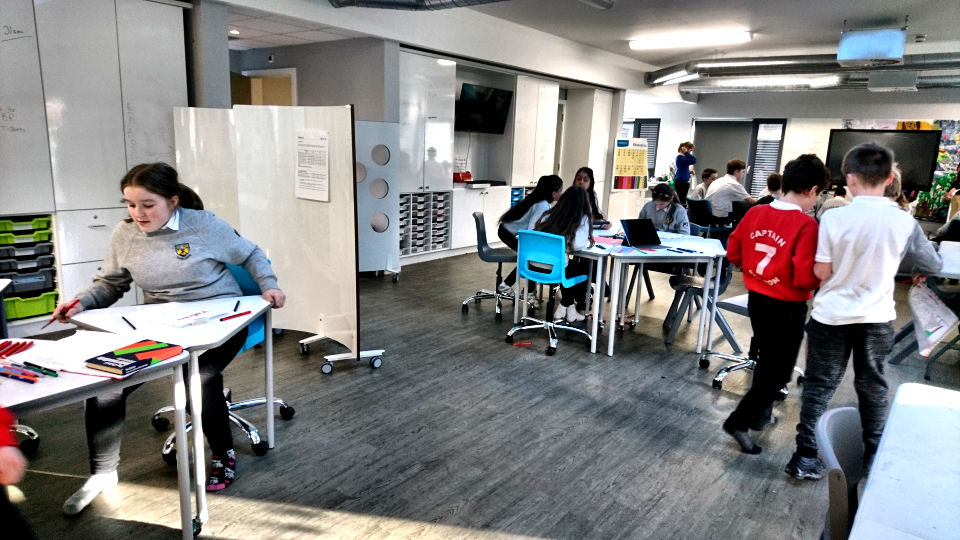a girl prepares to move her triangular table to face the teacher