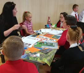 primary children sit around a table full of designs