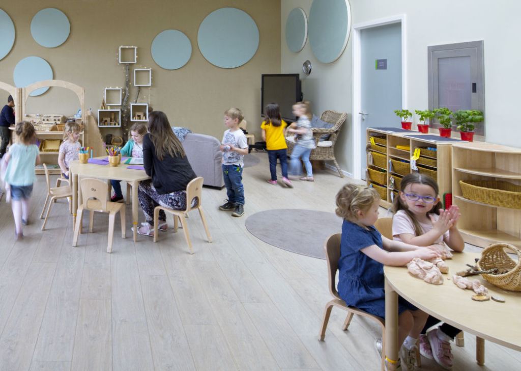 children are sitting at tables working in the nursery