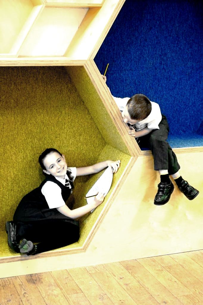 A boy and girl sitting in the hexagonal nooks