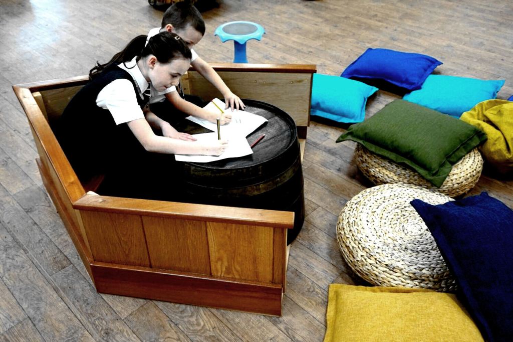 children writing at a fun boat shaped seat and desk