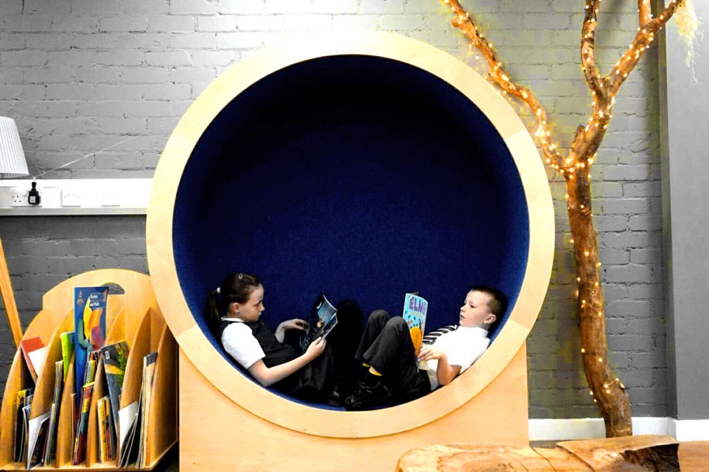 A boy and girl sit in the circular nook and read