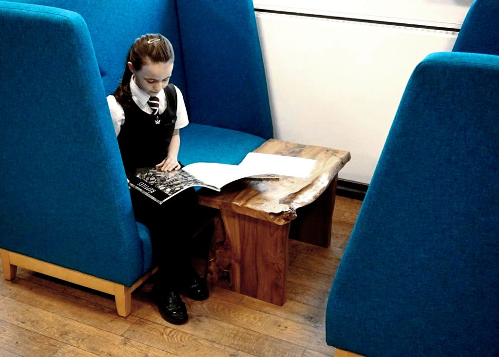 a girl reads sitting on a high backed sofa