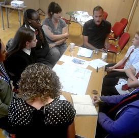 a group of high school students and their teachers sit around a table talking