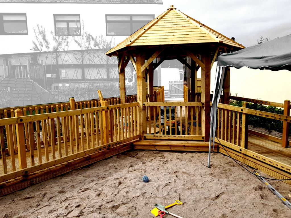 sandpit with a wooden walkway and roofed seating area