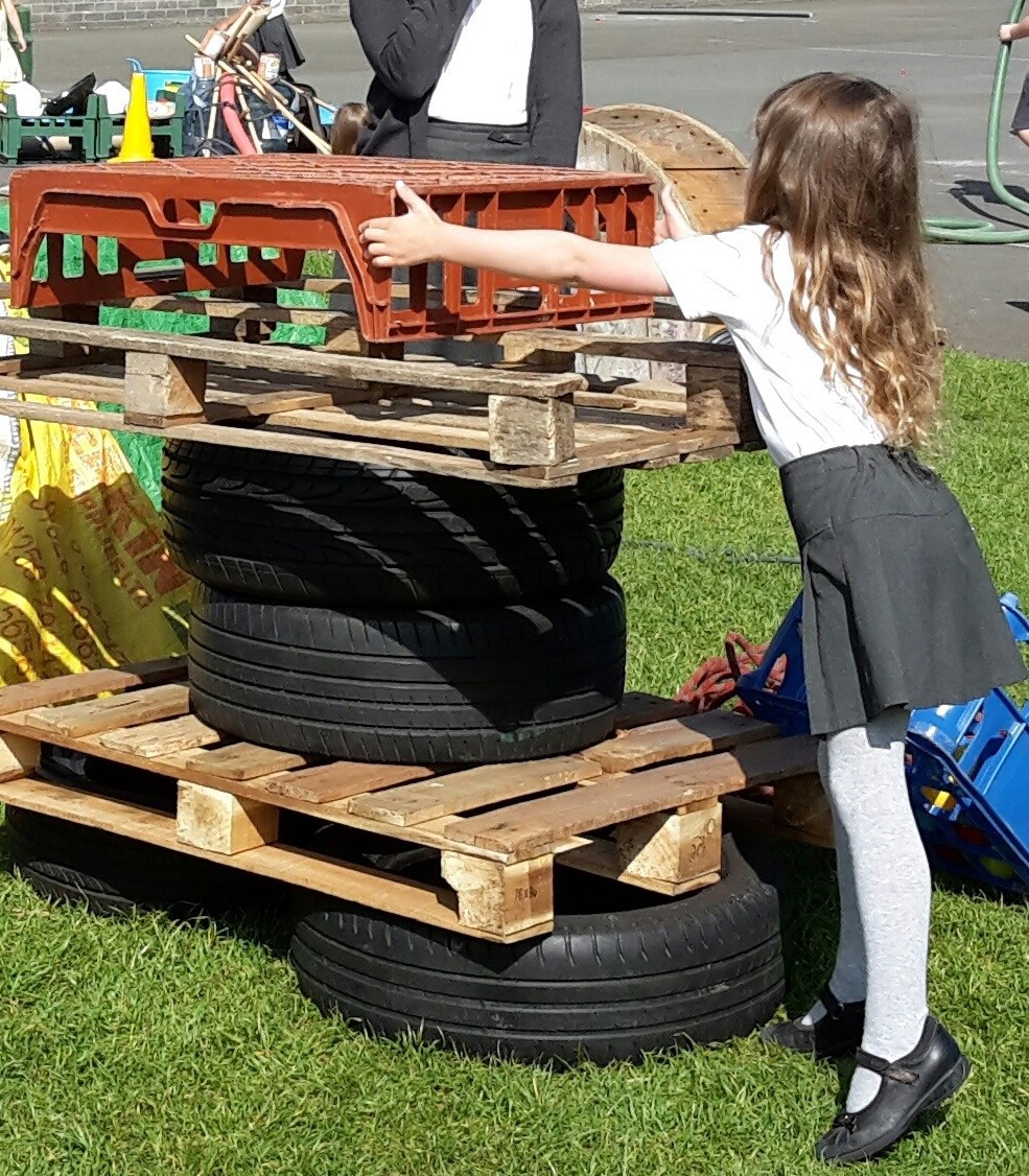 girl build a tower from tyres, palettes and crates