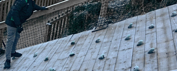 a child climbs on a sloping climbing wall