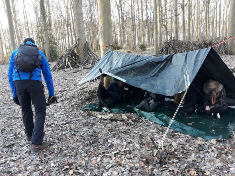 young people are sitting in a shelter they just made