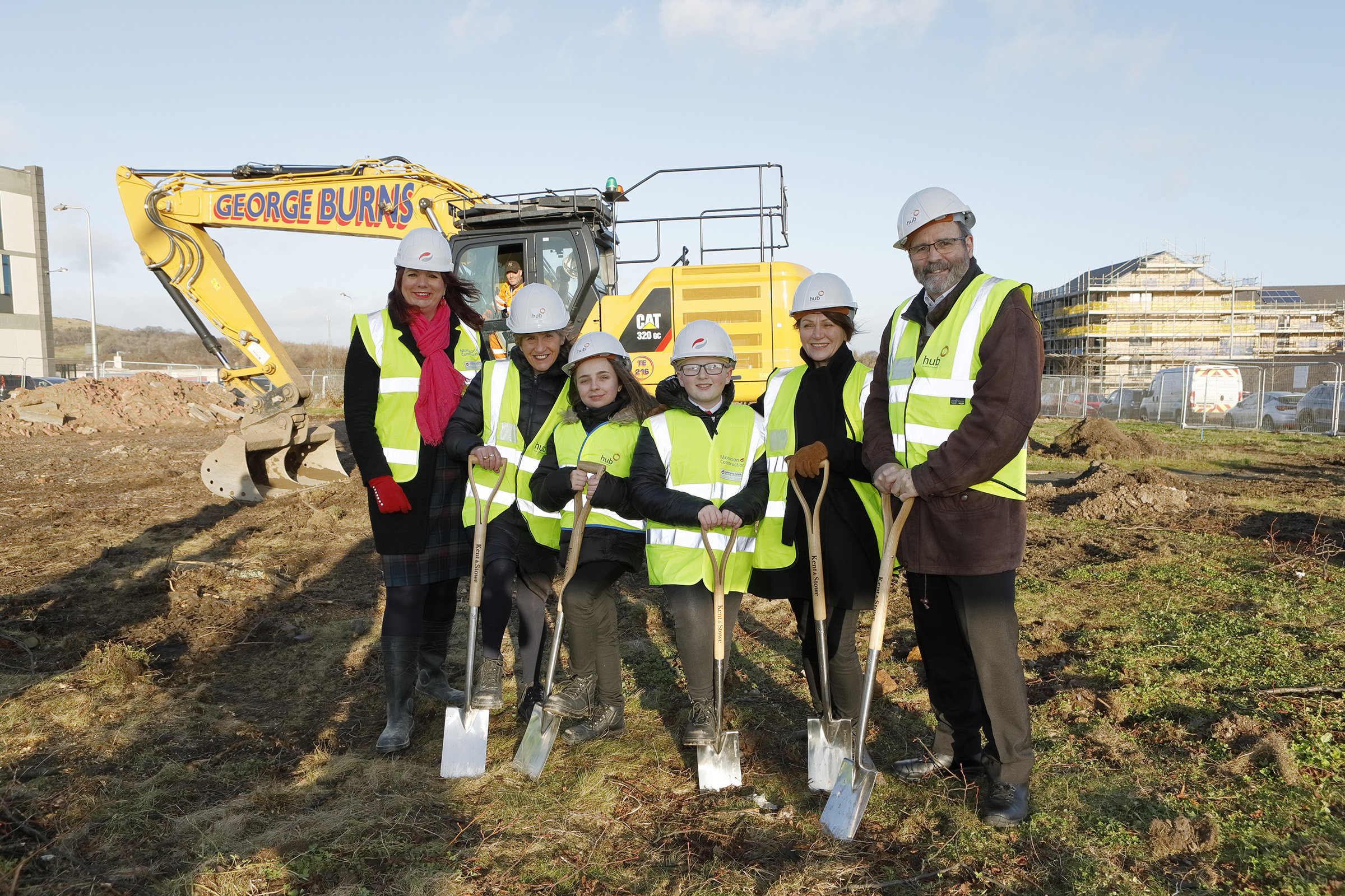 Councillors, staff and students stand on the site of the new school holding spades