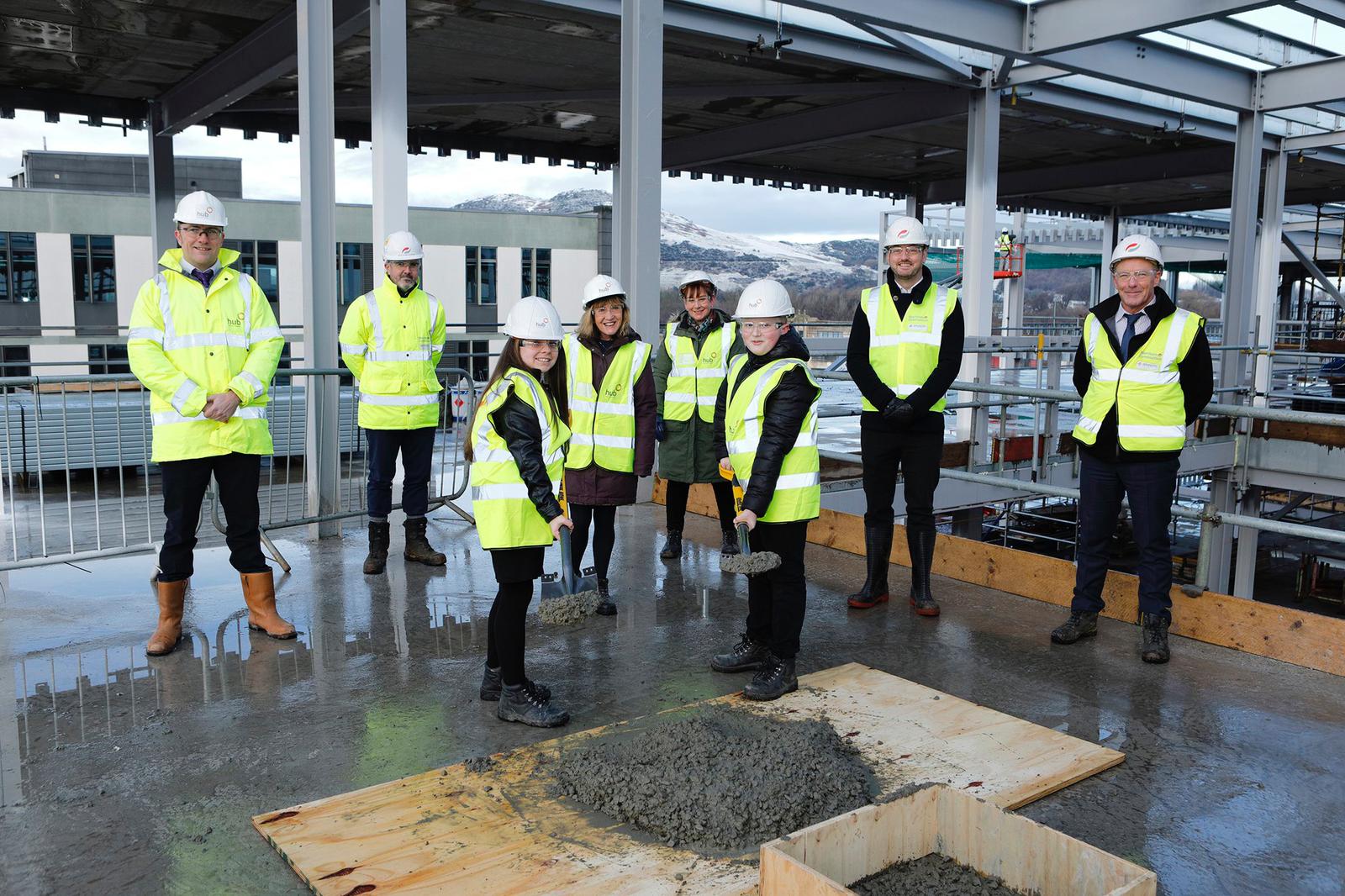 students stand with spades of cement for the Topping out ceremony of the new school