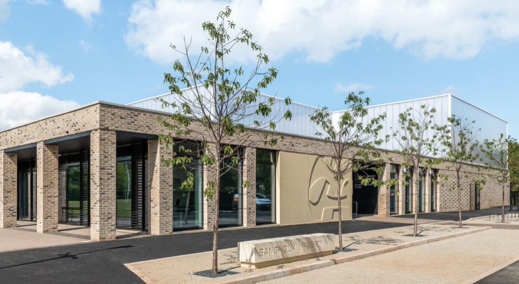 Front of the brick building with tree lined car park