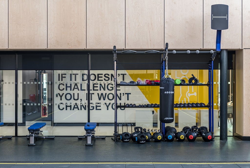 A large window in the fitness suite with views into the corridor weight lifting equipment in front.