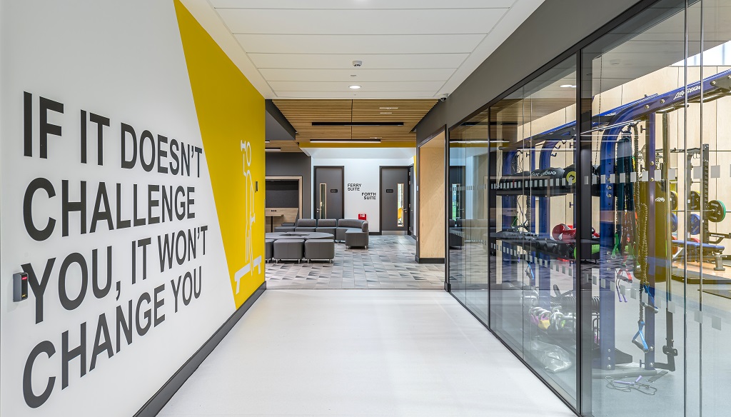 corridor beside fitness suite with slogan "if it doesn't challenge you, it won't change you"