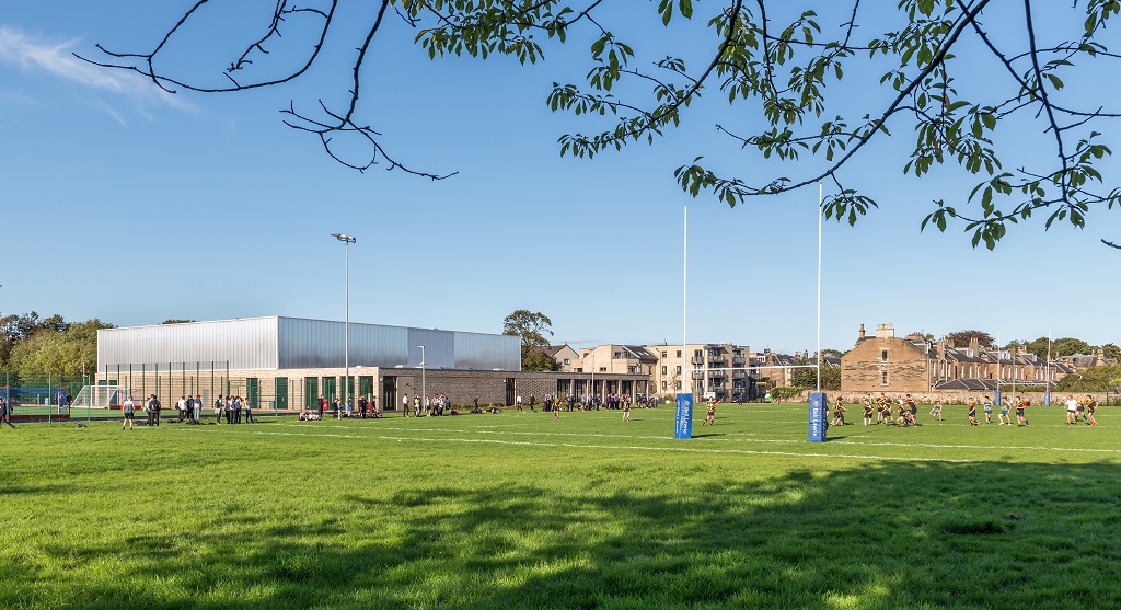 View of the building from the corner of the site looking out across the rugby pitch, students are playing rugby