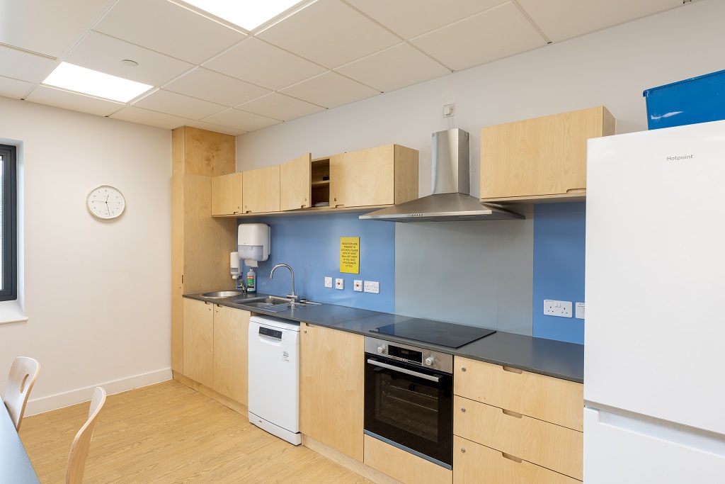 a kitchenette with oven, hob, fridge and sinks.