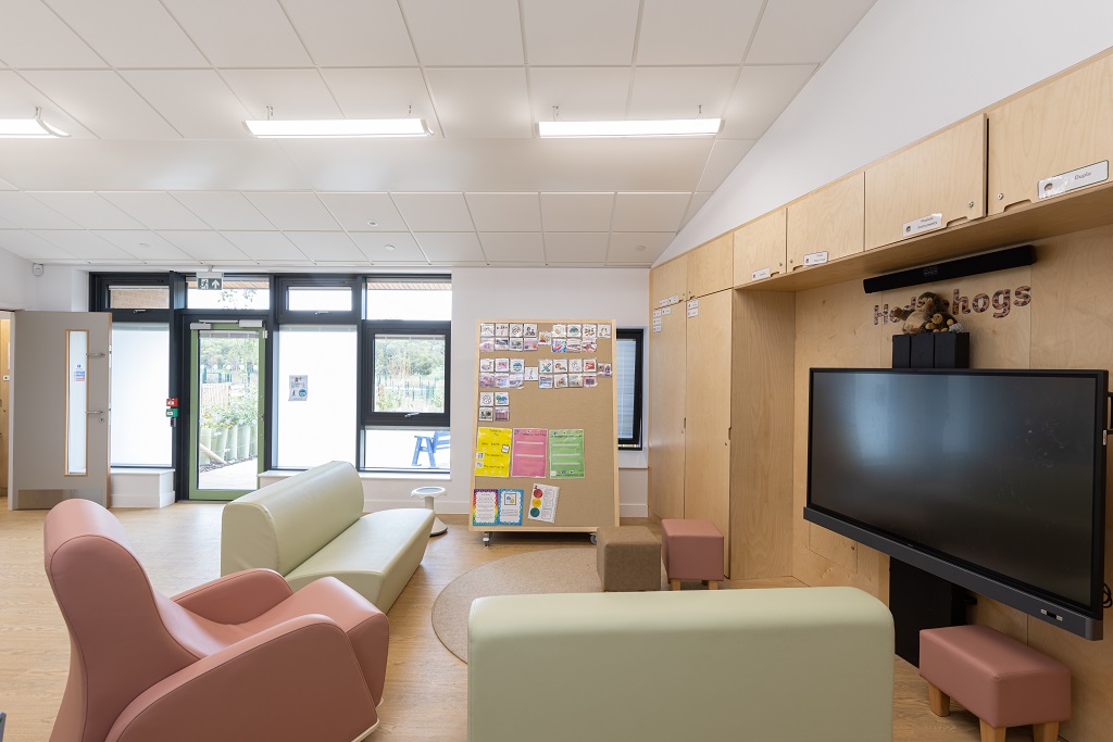 Classroom showing comfortable sofas and armchair in front of interactive screen