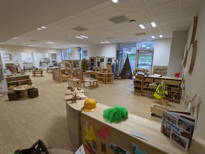 A neutrally decorated playroom, white walls and light wood flooring and furnishings
