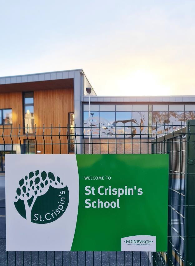 The entrance sign on the gate saying "welcome to St Crispin's school" in background is the new school building