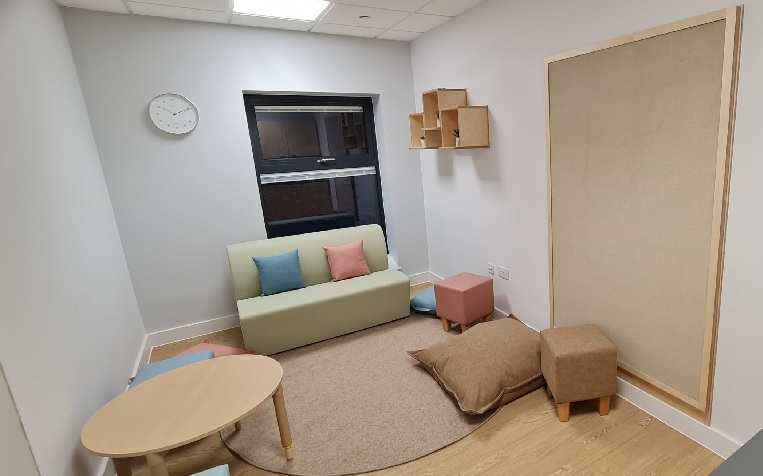 A small room with sofa, stools, coffee table, cushions and rug. A homely space.