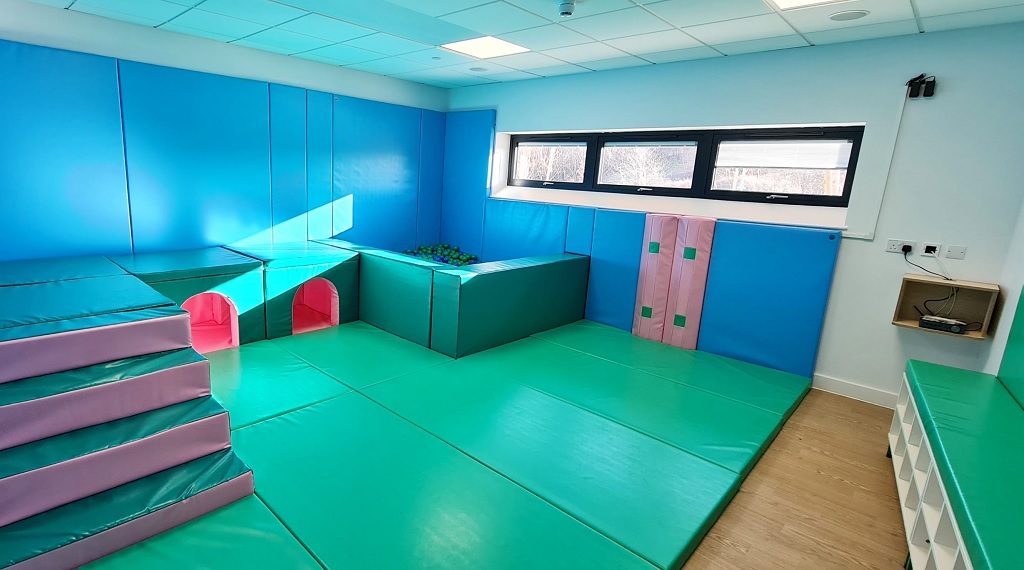 A soft play room, cushioned floor, benching, steps, tunnels and a ball pit