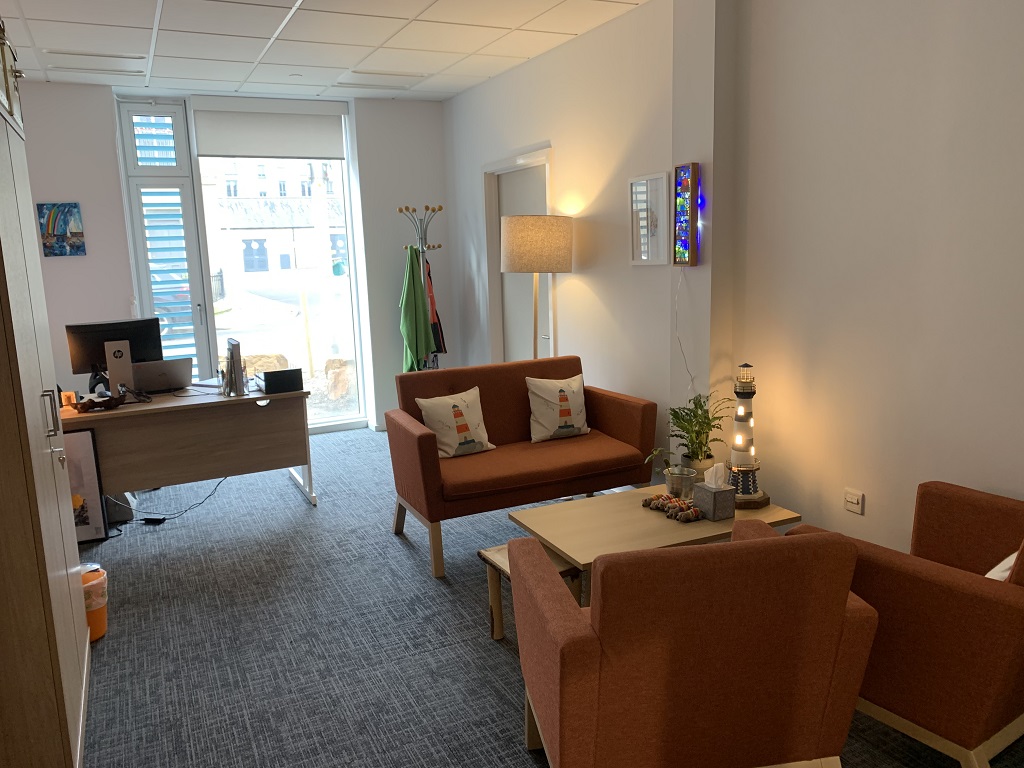 A cosy office with orange sofa and armchairs, homely furnishings